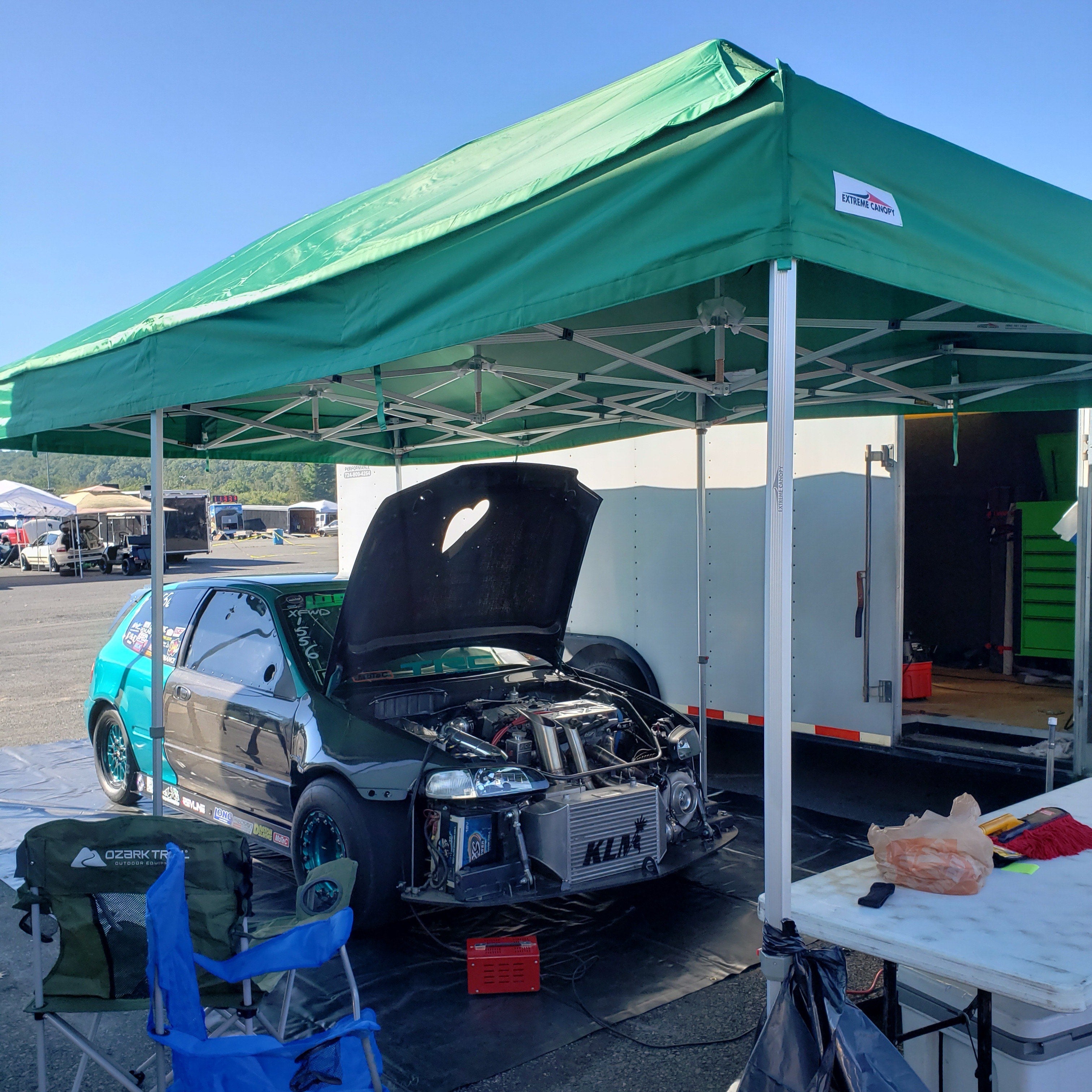 Green pop-up canopy tent providing shade at an outdoor motorsport event.