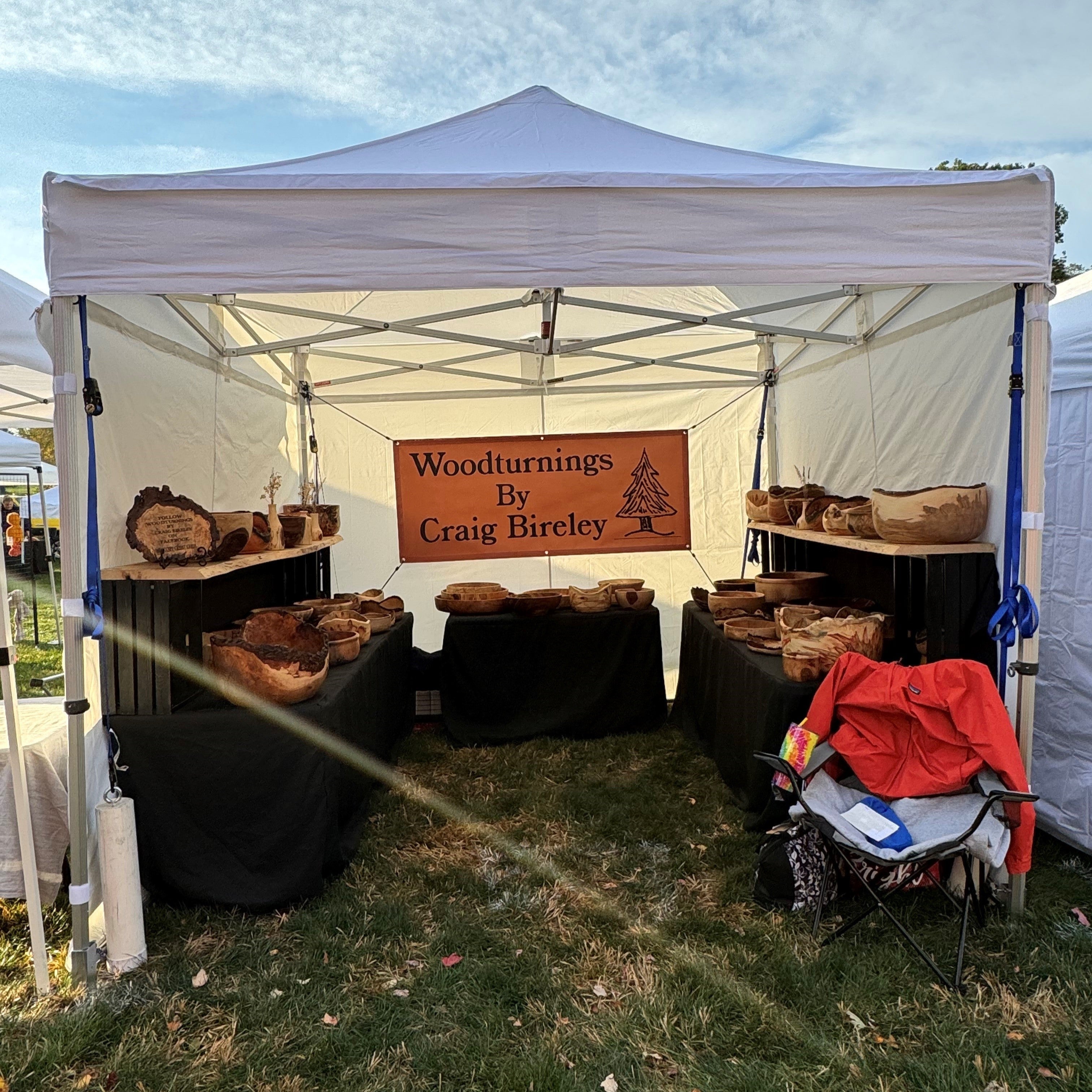 White canopy booth displaying handcrafted wooden bowls by Craig Bireley at an outdoor market.